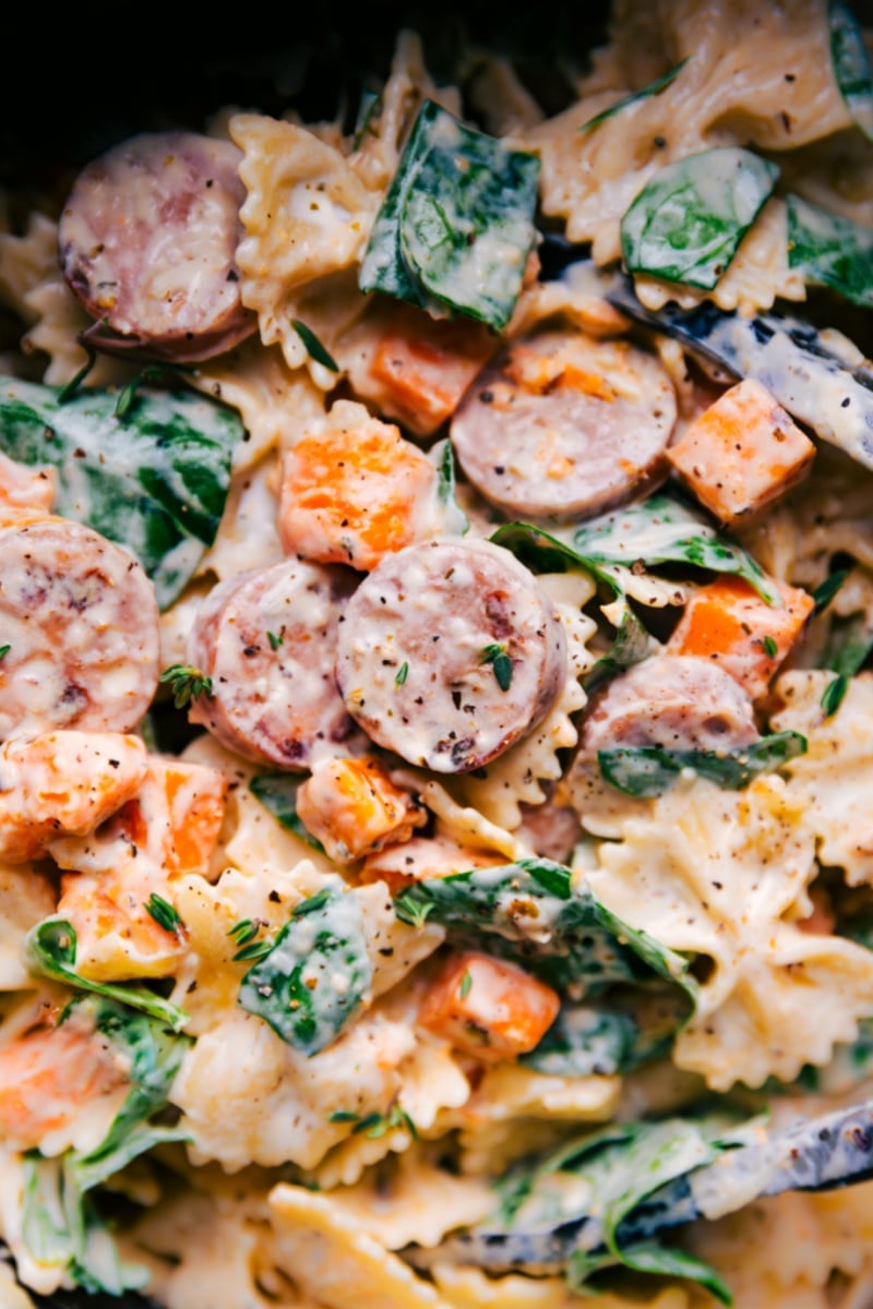 An indulgent Sweet Potato Pasta with roasted and seasoned sweet potatoes, onions, and chicken sausage. The pasta and veggies are tossed in an unforgettable creamy goat cheese sauce and topped with Parmesan. Recipe via ChelseasMessyApron #dinner #quick #easy #simple #best #bowtie #sausage #sweetpotato #pasta Overhead image of Sweet Potato Pasta