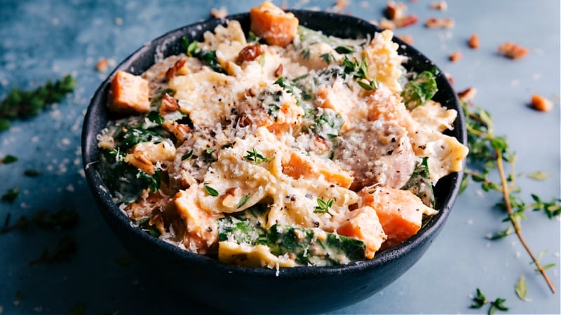 An indulgent Sweet Potato Pasta! The pasta and veggies are tossed in an unforgettable creamy goat cheese sauce and topped with Parmesan. Recipe via ChelseasMessyApron #dinner #quick #easy #simple #best #bowtie #sausage #sweetpotato #pasta Image of Sweet Potato Pasta in a bowl
