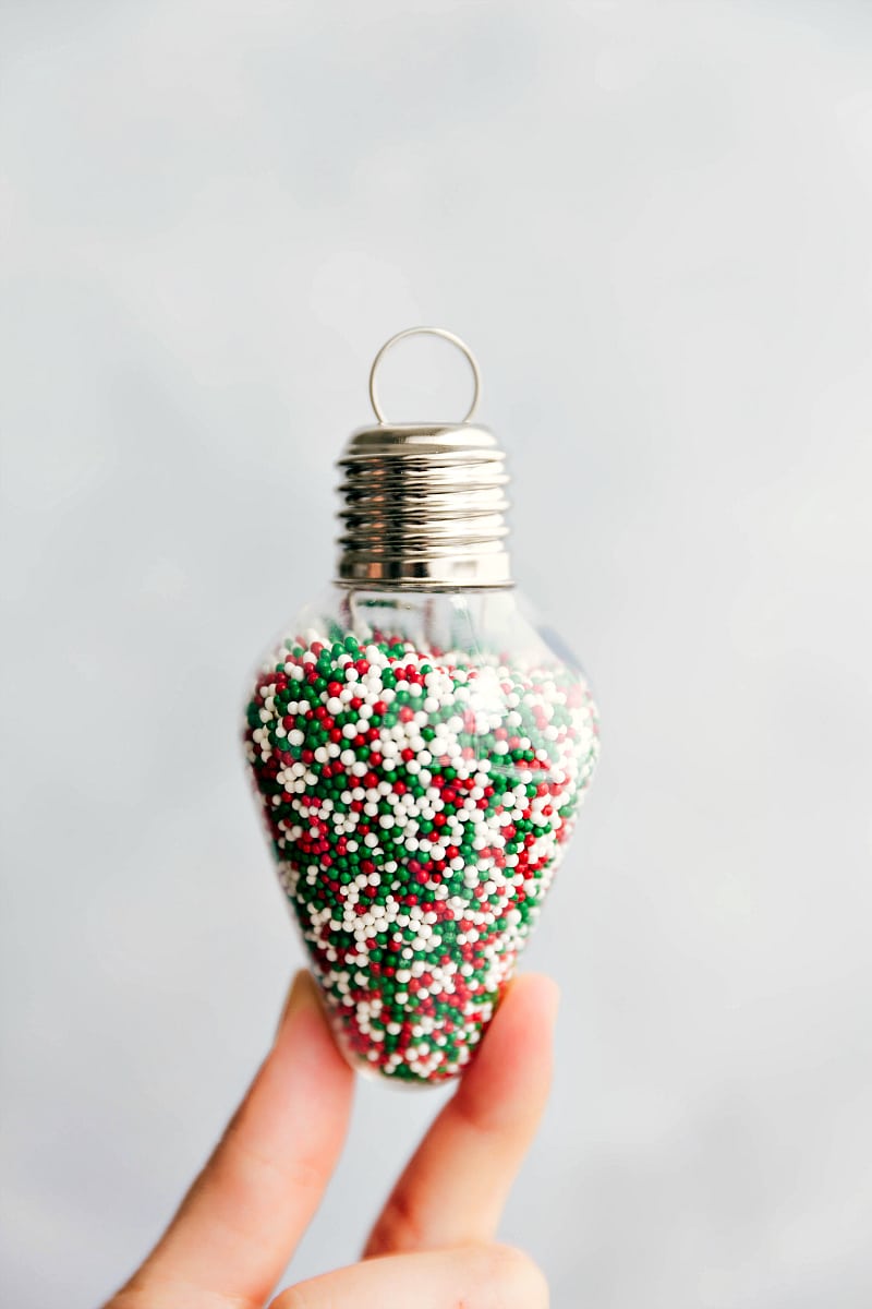 Here are some fun ideas to assemble your own Sugar Cookie Christmas Kits. These easy-to-assemble kits make a great gift! Recipe via ChelseasMessyApron.com #sugarcookies #cookiekit #gifts #makeyourown #christmascookies #sugarcookies #sprinkles #homemade Image of sprinkles in an ornament-shaped jar