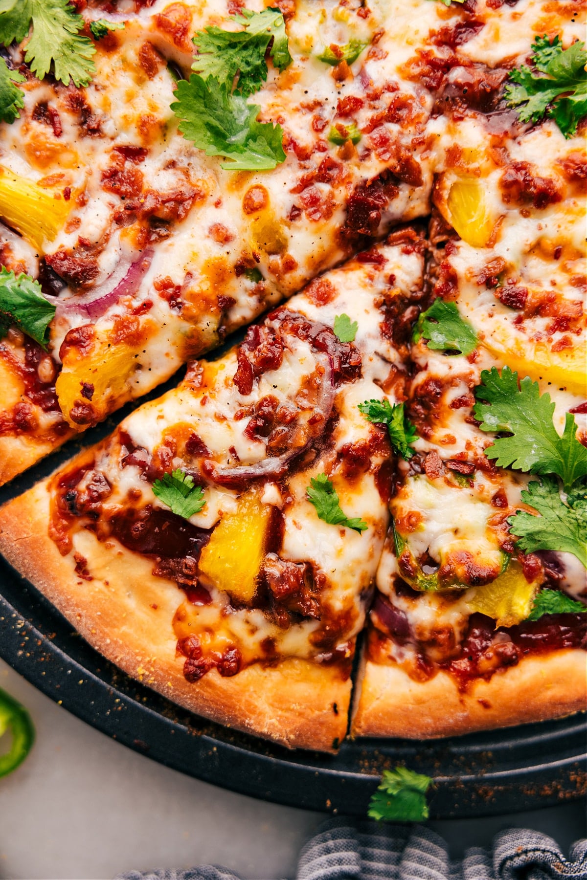 Easy And Delicious BBQ Chicken Pizza Recipe The dish fresh out of the oven with fresh cilantro on top and cut into slices.
