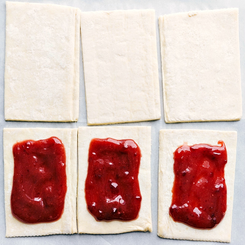Preparing Toaster Strudel: Puff Pastry with a Heart of Strawberry Jam Puff pastry pieces with strawberry jam dolloped in the center.