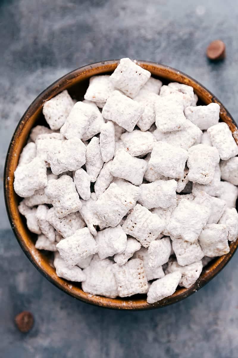 These Muddy Buddies (also called Puppy Chow) are the best easy treat. There's no baking required and only aย few ingredients!ย Recipe via ChelseasMessyApron.com #muddybuddies #puppychow #chex #chocolate #easy #treat #favorite Up-close overhead photo of a bowl of Muddy Buddies.