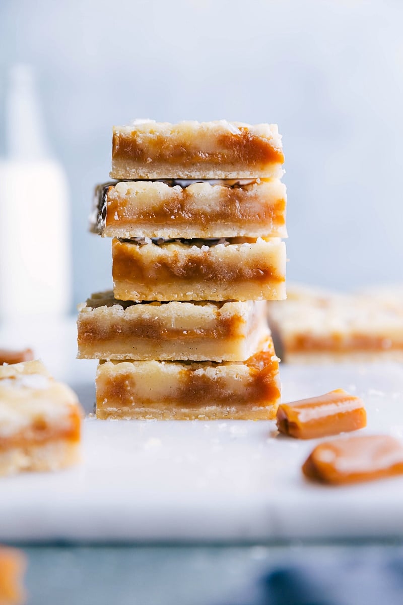 A stack of freshly baked caramel cookie bars, sliced to display a soft and gooey caramel-filled interior, surrounded by a crisp golden crust, rich in flavor.