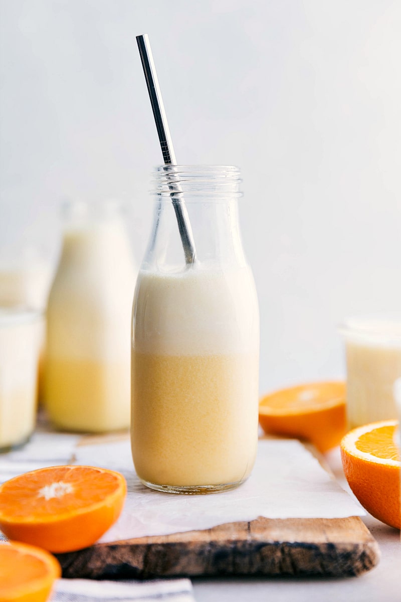 Our Favorite Orange Julius Recipe Ready-to-drink Orange Julius with a straw in it and cut oranges around it.