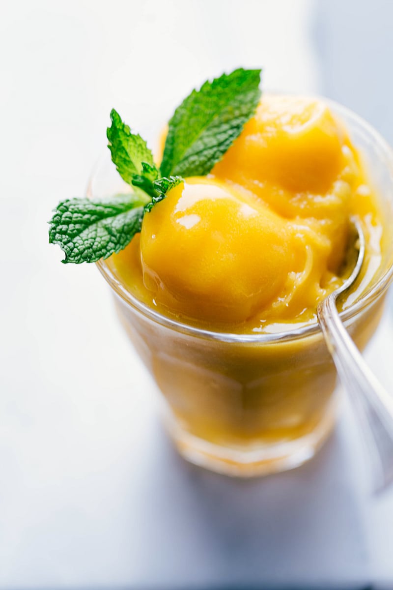 Our favorite creamy, fresh, tangy, and sweet Mango Sorbet is easy to make with honey mangoes and a hint of fresh lemon. Recipe via chelseasmessyapron #dessert #best #quick #easy #simple #refreshing #summer #mint #mango #sorbet Image of Mango Sorbet in a cup
