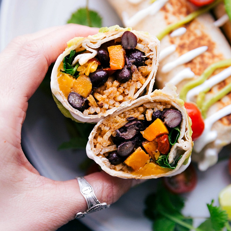 Cutting Healthy Burrito in Half to Reveal Filling: Beans, Sweet Potatoes, and Rice Cutting the meal in half to display the filling with beans, sweet potatoes, and rice spilling out.
