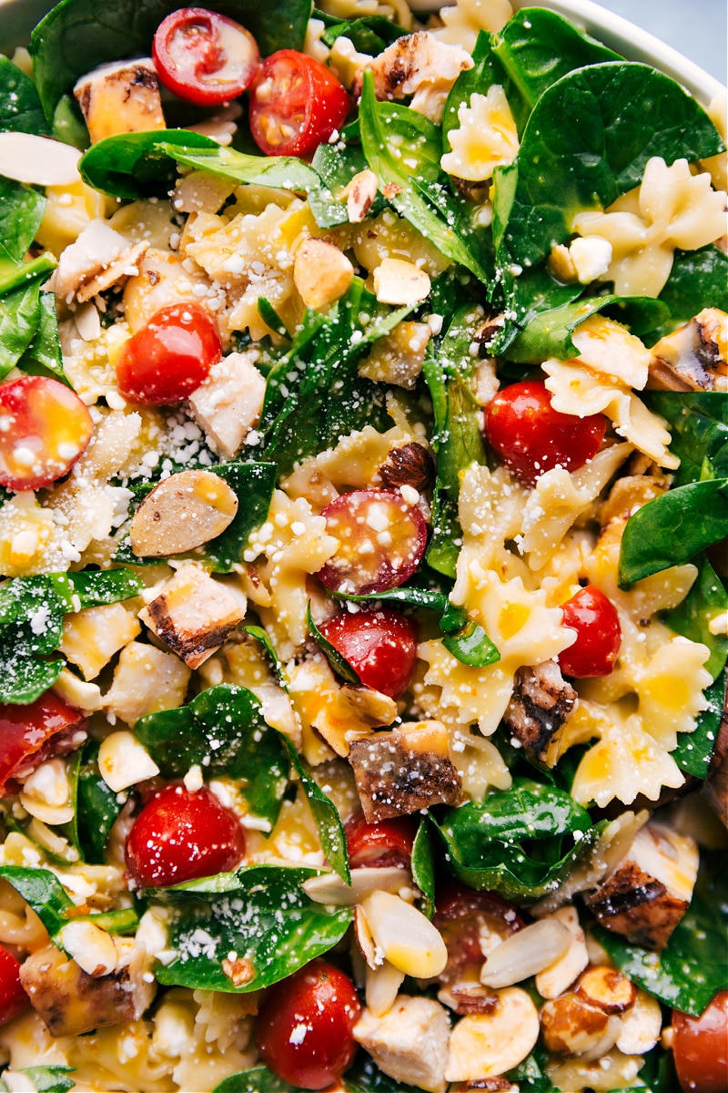 This Chicken Pasta Salad is brimming with goodness, from the rotisserie chicken to the pasta, to the veggies, the dressing and the toasted almonds! Recipe via ChelseasMessyApron #dinner #side #best #quick #easy #simple #healthy #spinach #bbq #bowtiepasta #chicken #pasta #salad Up close overhead image of the Chicken Pasta Salad