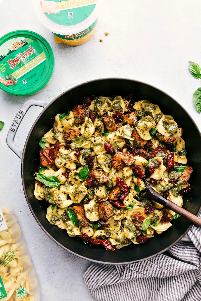 You'll love this one-pot, easy and quick Pesto Chicken Tortellini with sun-dried tomatoes and fresh basil! Recipe via chelseasmessyapron #recipes #pastasalad #greencolors #pesto #chicken #sundriedtomatoes Overhead image of the Pesto Chicken Tortellini in the pan.