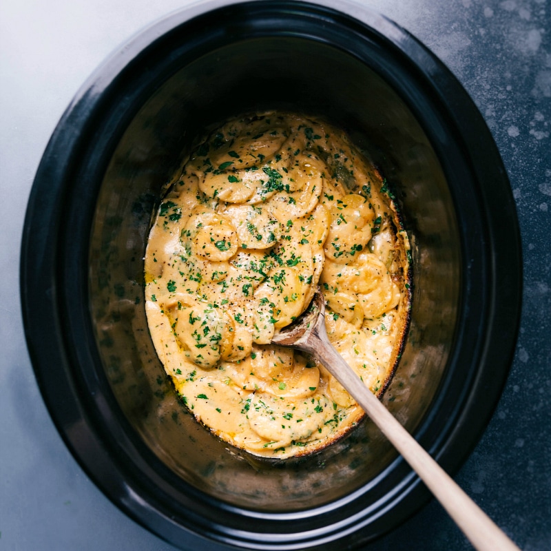 Crockpot Au Gratin Potatoes! Save that precious oven space during the holidays OR prepare these in the summer while keeping the oven off and the heat out of the kitchen -- the slow cooker is a lifesaver for either scenario! Recipe via chelseasmessyapron #dinner #quick #easy #simple #healthy #best #thanksgiving #familyfriendly #crockpot #augratin #potatoes Overhead image of the Crockpot Au Gratin Potatoes ready to be enjoyed