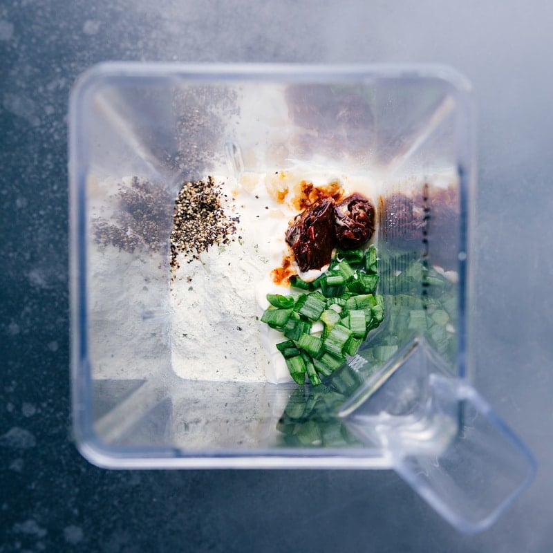 Chipotle Ranch Dip is an explosion of flavor and has a great kick of spice! Add everything to a blender and let it rip -- you'll be enjoying this dip in no time at all! Recipe via chelseasmessyapron #gameday #best #spicy #quick #easy #simple #blender #chipotle #ranch #dip Overhead image of all the ingredients in a blender, ready to be turned into Chipotle Ranch Dip.