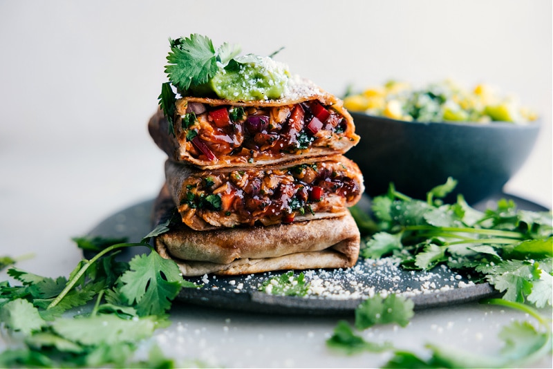 These BBQ Chicken Wraps are a delicious combination of saucy rotisserie chicken, sharp Cheddar cheese, and a mix of fresh veggies. They're not only absolutely delicious, but also a convenient meal that can be whipped up in no time! Recipe via chelseasmessyapron #dinner #quick #easy #simple #familyfriendly #kidfriendly #bbq #chicken #wraps Image of the BBQ Chicken Wraps stacked on top of each other