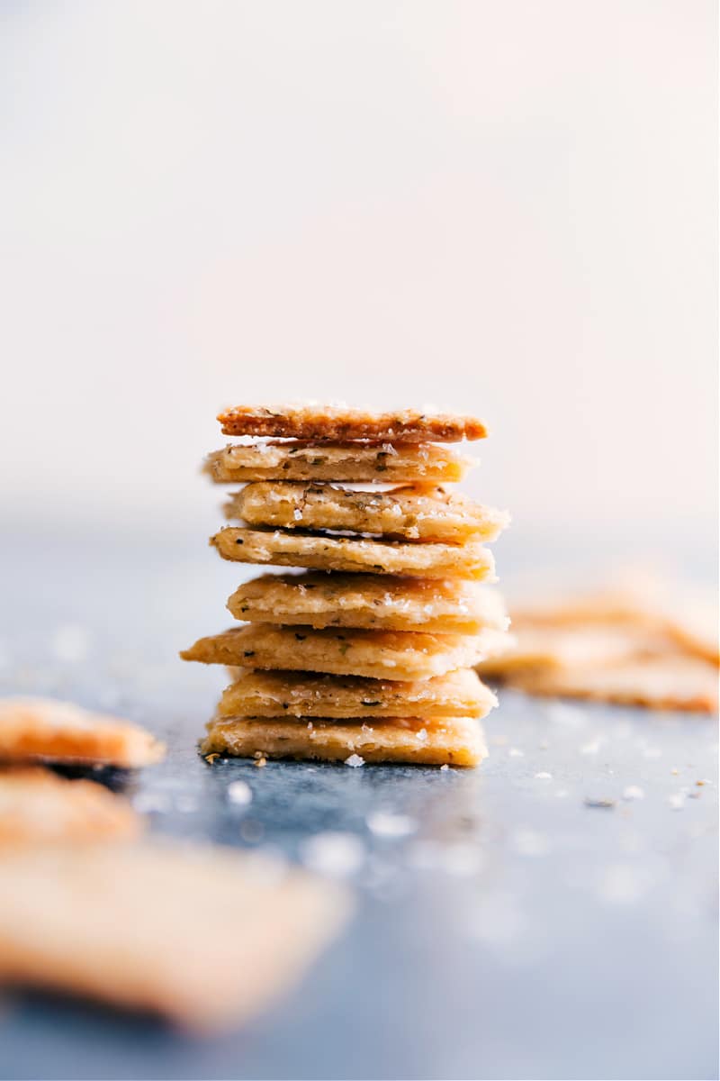 We're obsessed with these Homemade Crackers made with Parmesan cheese and Italian seasoning. Making crackers from scratch may seem excessive or intimidating, but we've simplified the process and are delivering a drool-worthy recipe. Once you try it, you won't forget it! Recipe via ChelseasMessyApron #snack #quick #easy #simple #best #homemade #crackers Image of the stacked Homemade Crackers
