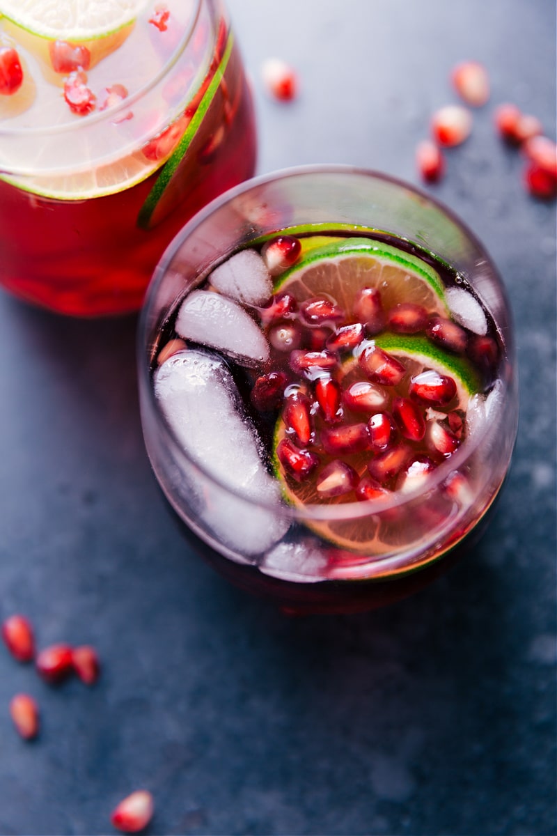 Sparkling Pomegranate Juice in a cup with fresh pomegranate seeds and limes in it.