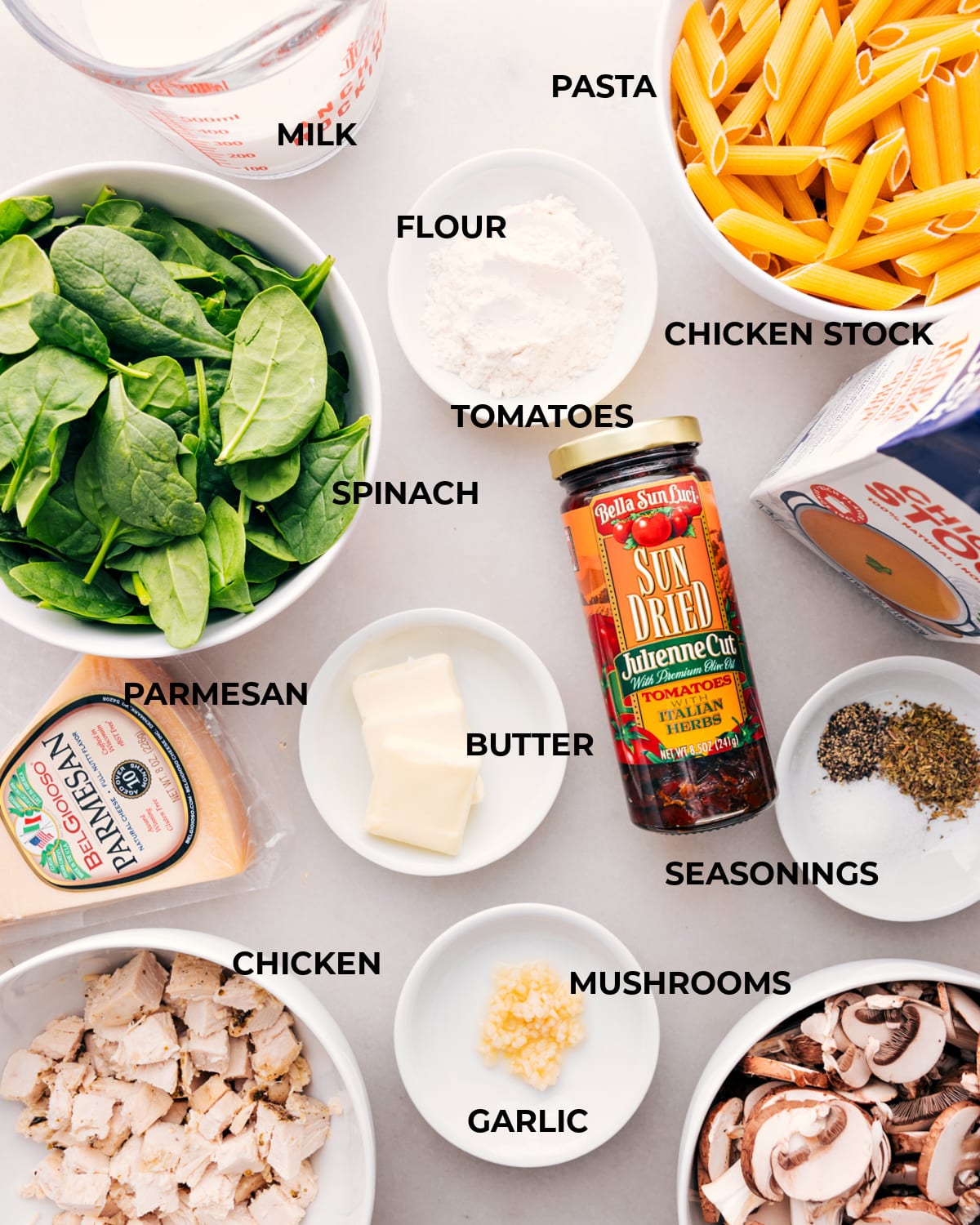 Pre-measured Ingredients for Chicken Penne Pasta Recipe Ingredients for Chicken Penne Pasta, including measured portions of chicken, penne, cheese, sun-dried tomatoes, mushrooms and spinach, are neatly laid out.