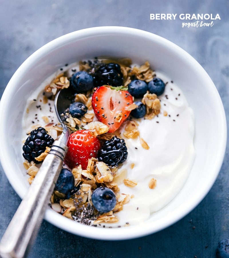 Berry-Granola Yogurt Bowl: A Scrumptious Breakfast with Fresh Berries and Granola Berry-granola yogurt bowl topped with fresh berries and granola, accompanied by a spoon, prepared for a delightful meal.