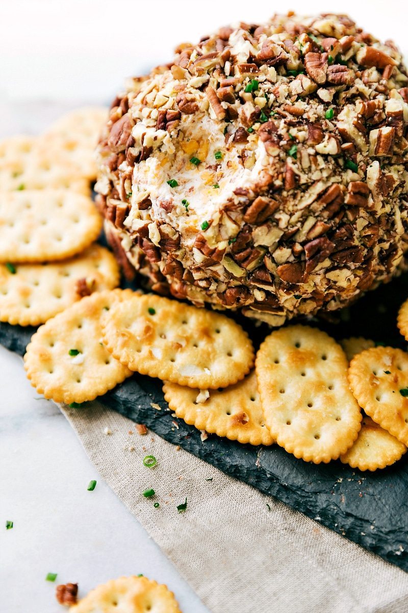 Gorgeous Cheese Ball with Crackers - Ready to Enjoy as a Delicious Snack A gorgeous cheese ball with crackers on the side, and a bite scooped out of it, ready to be enjoyed as both a delicious and visually appealing snack.