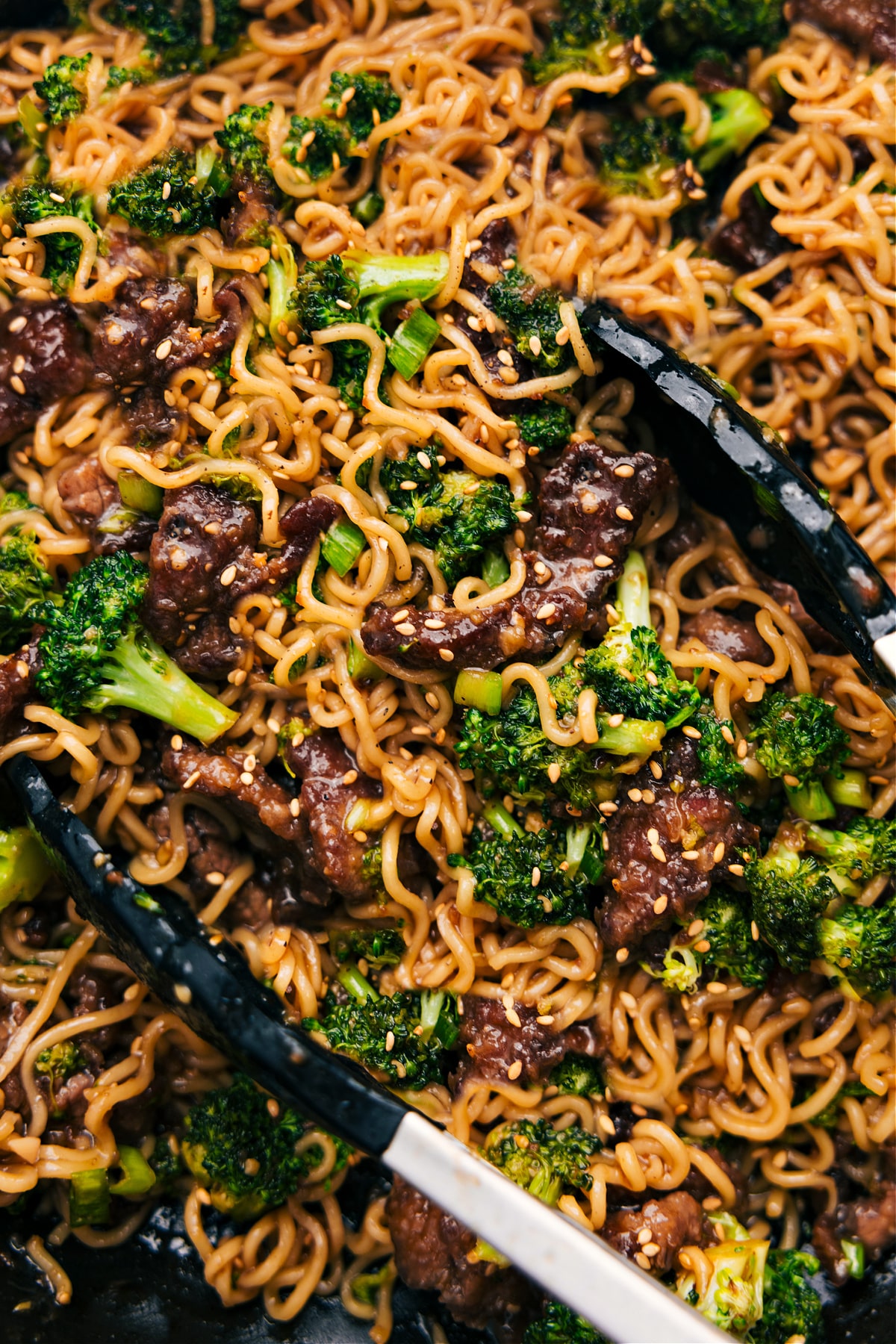Top Your Beef And Broccoli Ramen With Green Onions And Sesame Seeds Beef and broccoli ramen in the pot with sesame seeds and green onions as garnish.