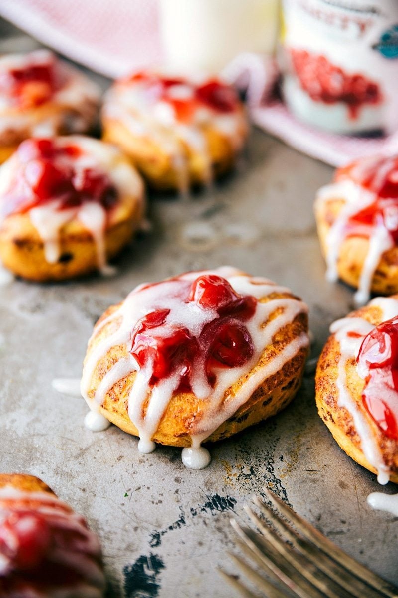 The easiest, 5-Ingredient, 30-minute (OR LESS) Cherry Danish Cinnamon Rolls! Recipe via chelseasmessyapron.com #cherry #danish #cinnamonrolls #quickeasy #breakfast #pastry View of Cherry Danishes on a baking sheet