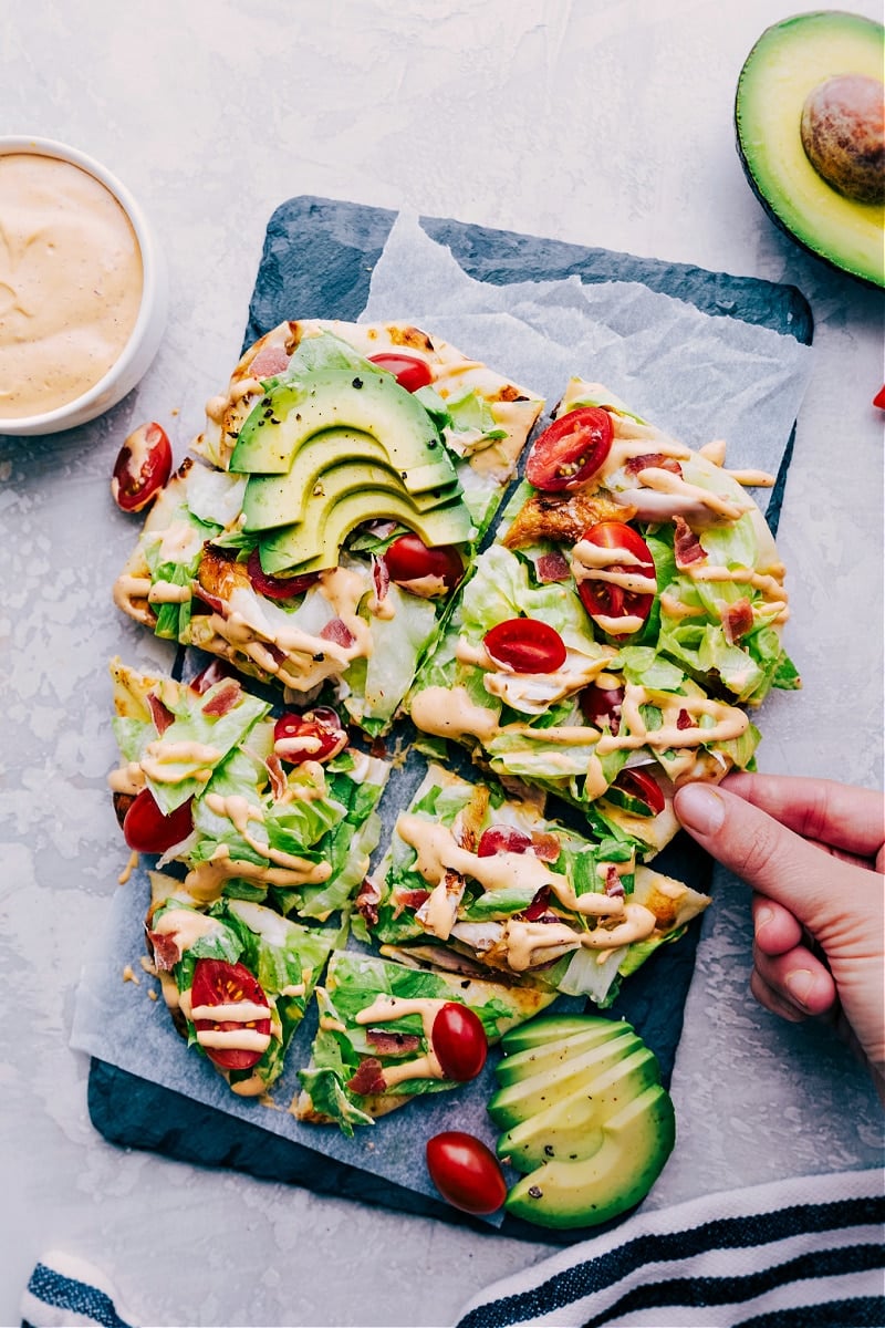 Chipotle Chicken Flatbread! After that comes out of the oven, we top it with some iceberg lettuce, cherry tomatoes, and ripe, creamy avocados. A sprinkling of crispy bacon and drizzle of the most addicting chipotle ranch dressing and you're in dinner heaven! Recipe via chelseasmessyapron #dinner #quick #easy #simple #best #oven #sauce #chipotle #chicken #flatbread Chipotle Chicken Flatbread sliced and ready to be served