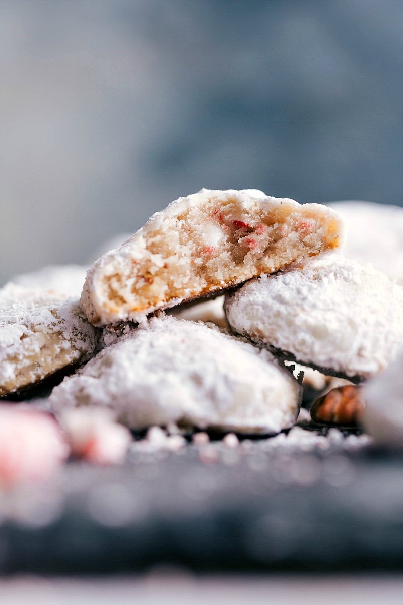 Peppermint Snowball Cookies Stacked with a Bite Revealing Moist and Flavor-Packed Interior Delicious and seasonal desserts stacked on top of each other, with a bite out of one revealing the moist and flavor-packed interior.