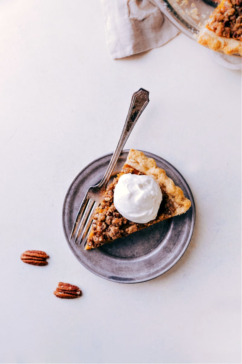 Pumpkin pecan pie slice topped with maple whipped cream.