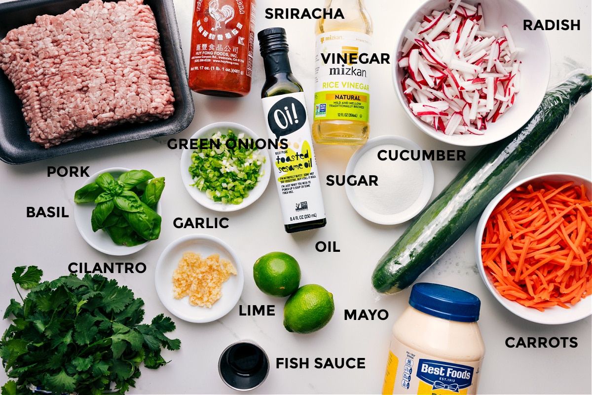 Ingredients In Banh Mi Bowls All the ingredients for this recipe prepped and ready for easy assembly, including pork, sriracha, vinegar, oil, green onions, basil, cilantro, garlic, lime, mayo, fish sauce, carrots, cucumber, sugar, radishes, and vinegar.
