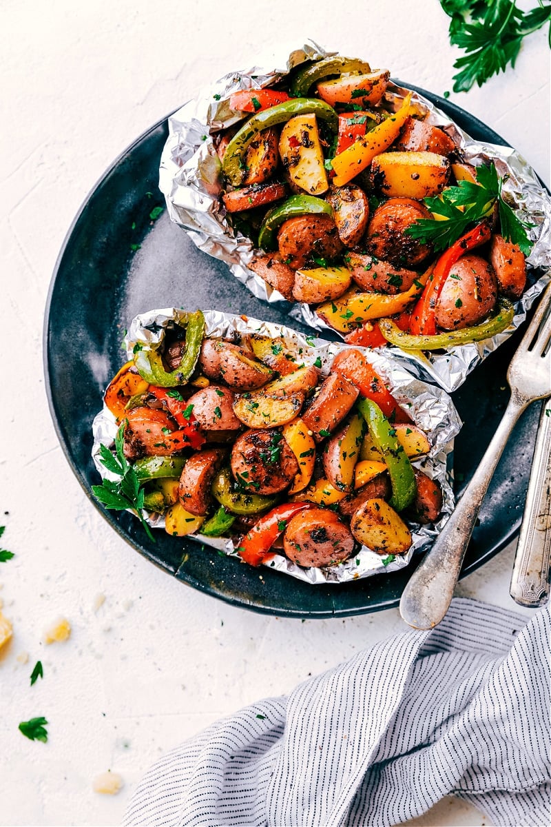 These delicious Foil Pack Sausage and Veggie meals combine smoked sausage, sweet bell peppers, savory mushrooms, tender potatoes, minced garlic, and diced yellow onions with olive oil and an incredible Italian-inspired seasoning blend. Wrap everything in some foil and bring them along camping or cook them on the grill. No campfire or grill? No problem, these family-friendly foil packs can also be baked in the oven! Recipe via ChelseasMessyApron #dinner #quick #easy #simple #oven #grilled #camping #best #healthy #keto #peppers #foilpack #italian #sausage #veggies Foil Pack Sausage and Veggies