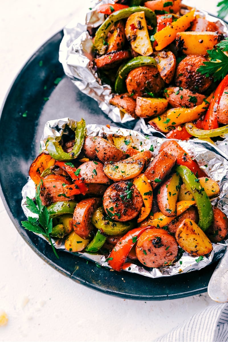 These delicious Foil Pack Italian Sausage and Veggies meals combine smoked sausage, sweet bell peppers, savory mushrooms, tender potatoes, minced garlic, and diced yellow onions with olive oil and an incredible Italian-inspired seasoning blend. Throw everything in some tin foil and bring it along camping or throw it on the grill. Recipe via ChelseasMessyApron #dinner #quick #easy #simple #oven #grilled #camping #best #healthy #keto #whole #whole30 #peppers #foilpack #italian #sausage #veggies Foil Pack Italian Sausage and Veggies on a plate