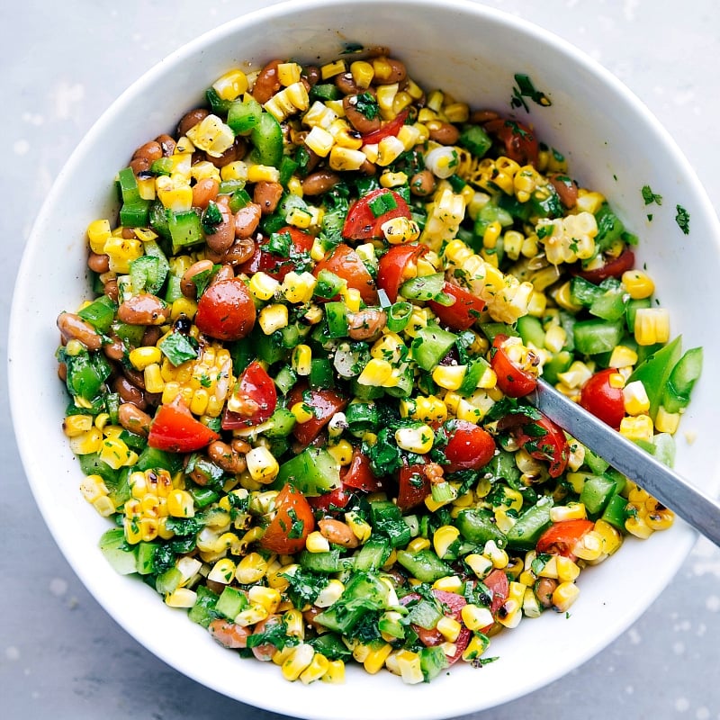 Flavor-Packed Corn Salsa for Burger Side A bowl filled with flavor-packed corn salsa, which serves as a delightful side for this meal, featuring a vibrant blend of ingredients.