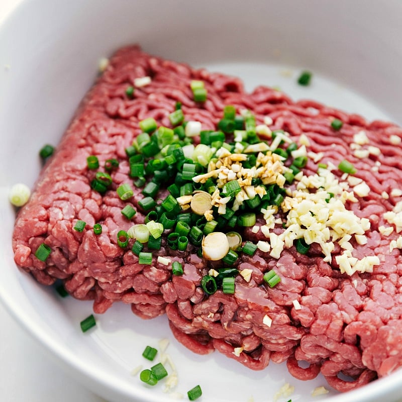 Combining Ground Beef with Diced Green Onions and Seasonings Combining ground beef with diced green onions and a blend of seasonings, capturing the initial step in preparing the best burger recipe.