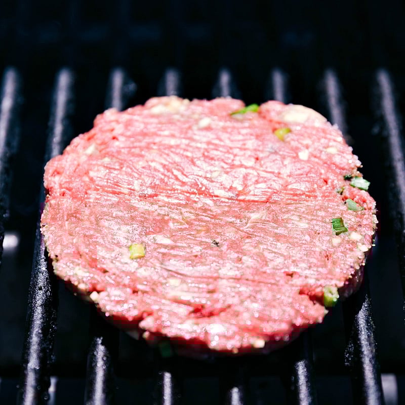 Grilling Beef Patty to Perfection A beef patty sizzling on the grill, being cooked to perfection, ensuring a juicy and flavorful patty.