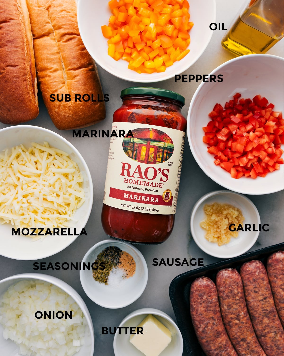 Ingredients In Italian Sausage Sandwich All the ingredients for this recipe are prepped and ready for easy assembly, including peppers, rolls, marinara, mozzarella, onion, seasonings, sausage, garlic, and butter.
