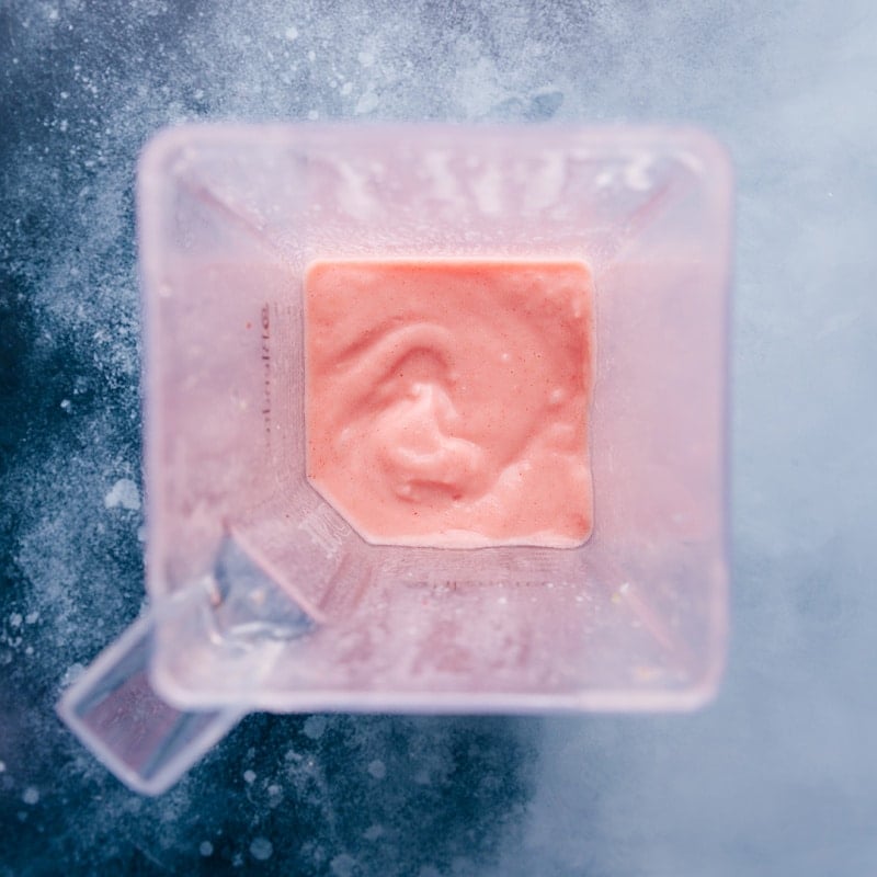 Adding strawberries makes for a fun and unique take on the classic frozen Pina Colada. (This beverage is non-alcoholic.) Recipe via chelseasmessyapron #breakfast #quick #easy #simple #delicious #snack #pineapple #tropical #best #frozen #strawberry #pinacolada #smoothies Overhead view of the piña colada in the blender.