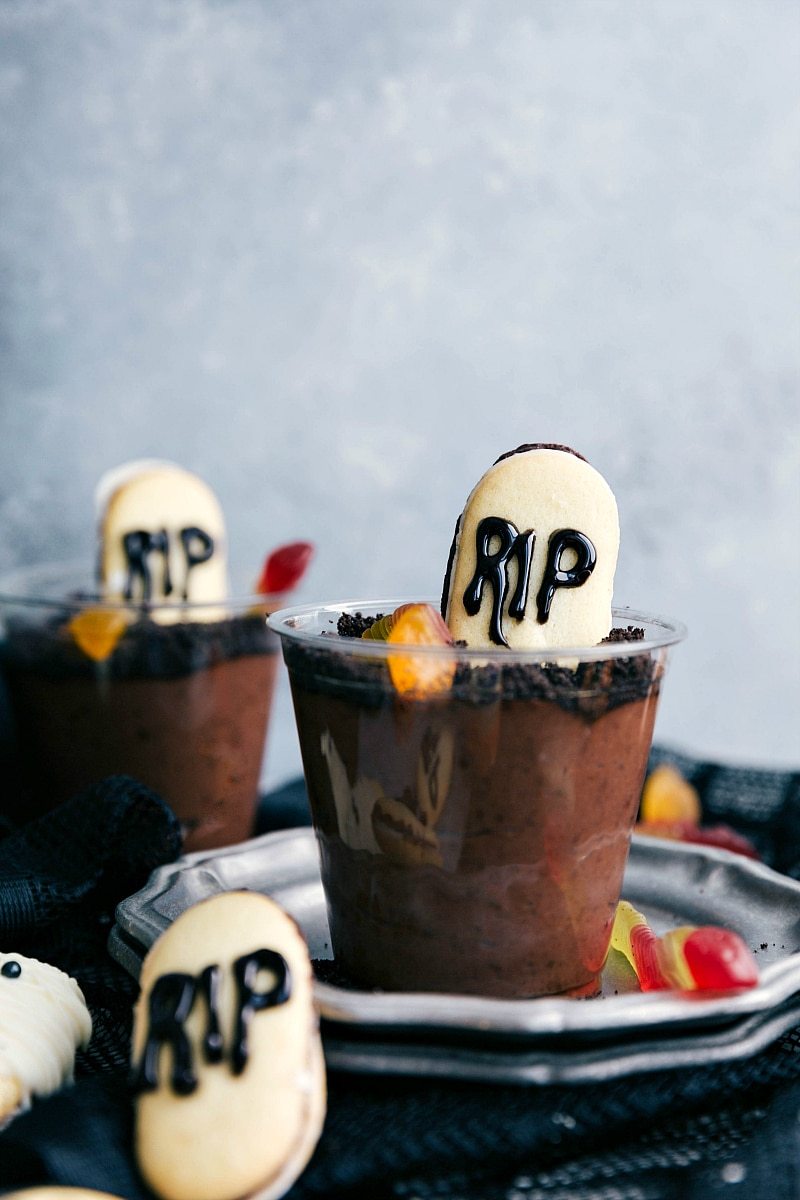 GRAVEYARD PUDDING CUPS | 5 super easy Halloween treats -- mummy cookies, graveyard pudding cups, Frankenstein krispies, pumpkin krispies, and double-sided Halloween sandwich cookies. These treats are perfect for Halloween treats to make at home.ย I chelseasmessyapron.com Picture of the graveyard pudding cups that go along with these easy halloween treats