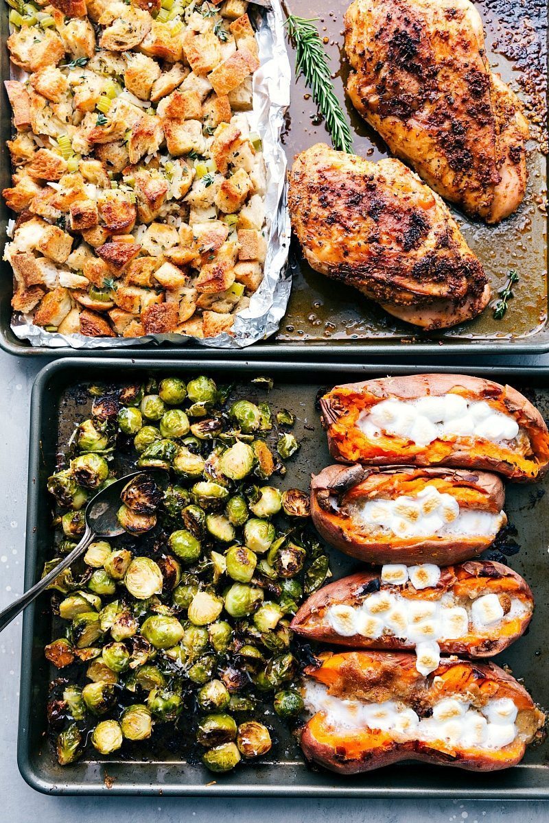 Sheet Pan Thanksgiving Meal with Turkey and Sides Two sheet pans with roasted turkey, stuffing, brussel sprouts, and sweet potatoes fresh out of the oven.