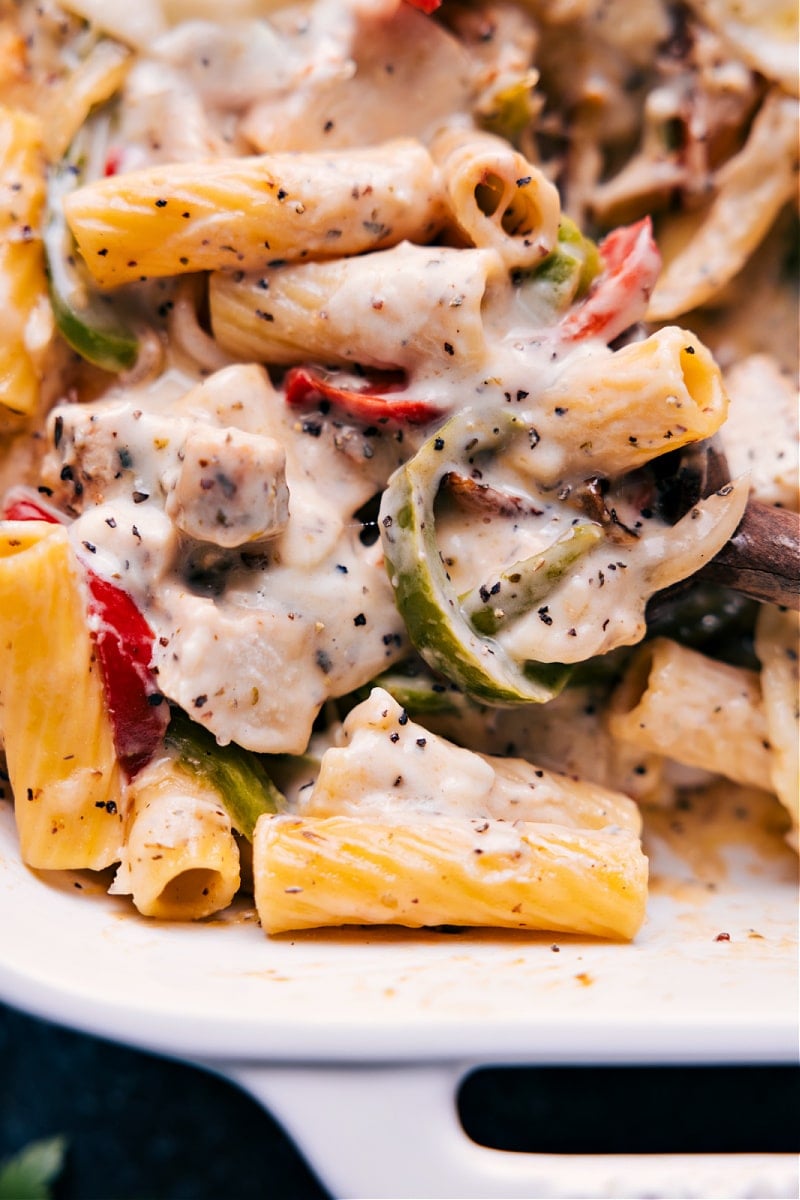 Creamy and cheesy Baked Ziti With Chicken is a deeply savory and totally indulgent meal the whole family will go crazy for! We're channeling the flavors of a good chicken cheesesteak into this gooey pasta dish by combining perfectly cooked pasta with sautรฉed peppers and onions, seasoned chicken, and plenty of melty Provolone cheese. Recipe via ChelseasMessyApron.com #chicken #cheesesteak #bakedziti #provolone #casserole #cheesy Closeup view of Baked Ziti With Chicken