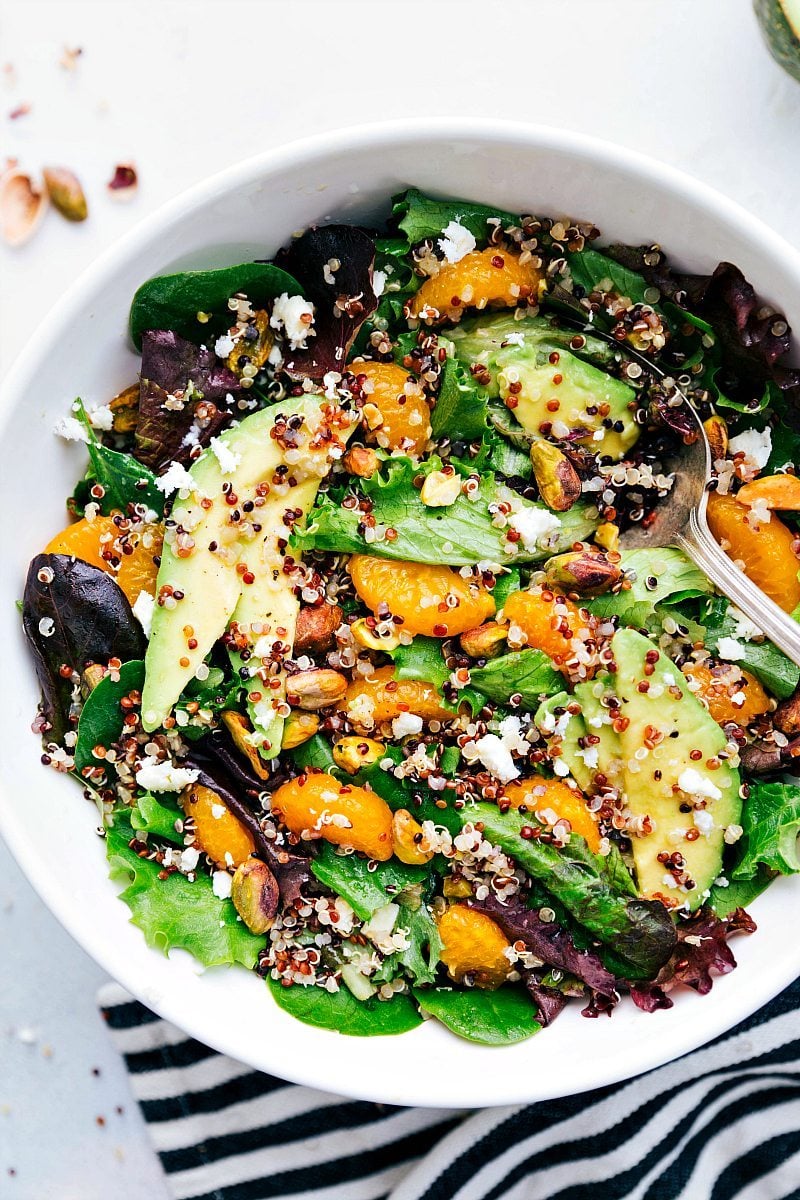 Nutritious, fresh, and flavorful Citrus Quinoa Salad overflows with clementine oranges, roasted pistachios, creamy avocado, and goat (or feta) cheese. This salad is drizzled with a tangy and sweet citrus vinaigrette. Recipe via chelseasmessyapron #healthy #detox #clean #whole #mixedgreens #nutrients #pistachio #citrus #quinoa #salad Up-close overhead image of Citrus Quinoa Salad, ready to be served