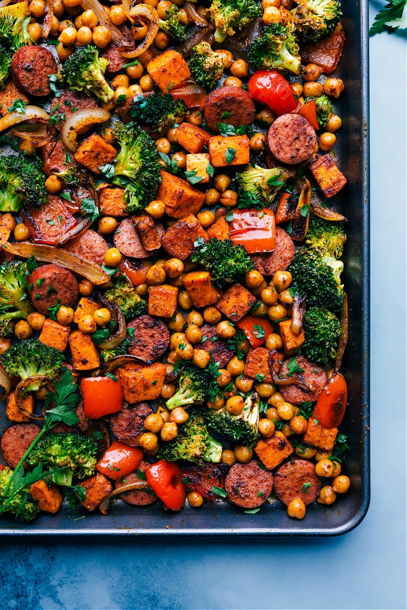 The best ever Sausage and Chickpeas! This meal is prepared on one sheet pan requiring minimal prep time and even quicker cleanup! Recipe via ChelseasMessyApron #broccoli #onions #peppers #sausage #chickpeas Overhead image of the pan fresh out of the oven