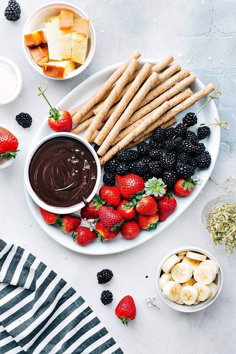 The best easy chocolate fondue recipe in a bowl with all the delicious treats to dip in it.