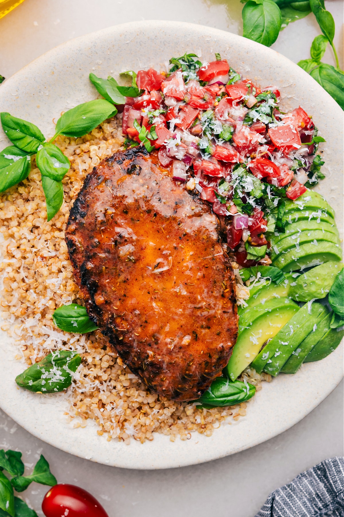 Bruschetta Chicken on a bed of quinoa with fresh bruschetta and avocado on the side.