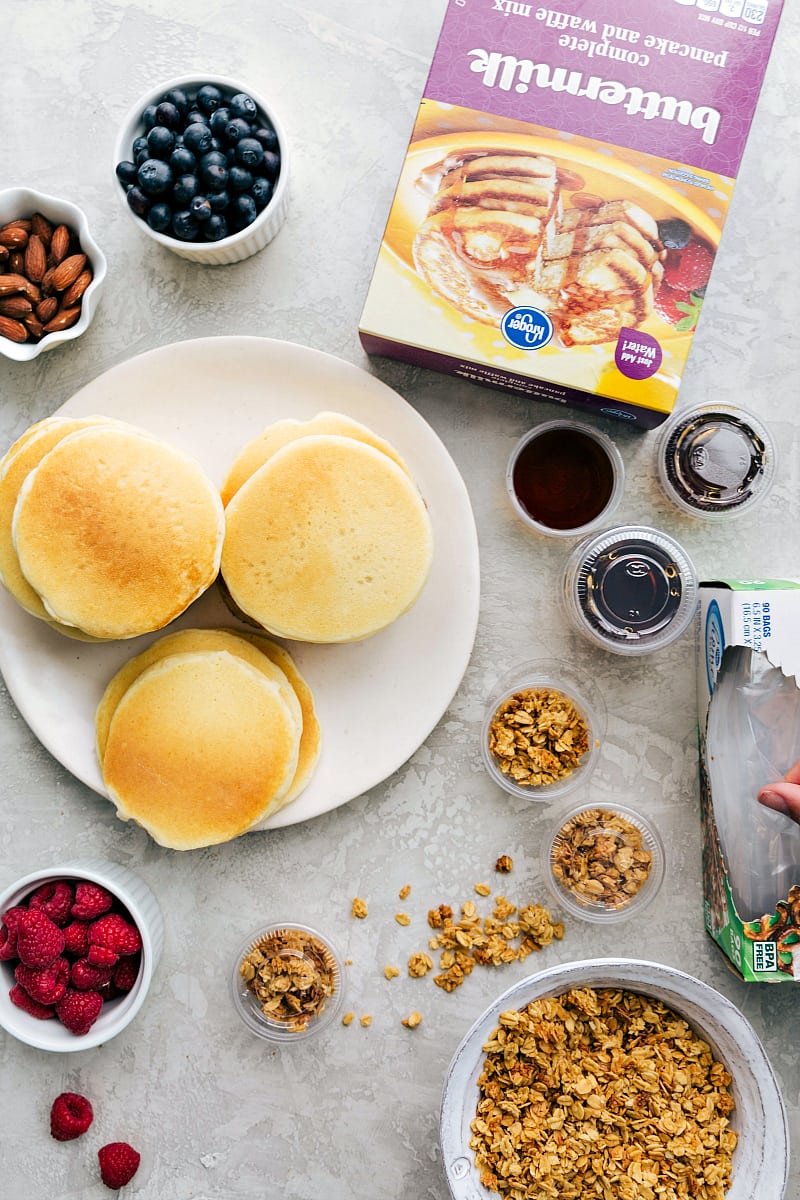 Kids School Lunch Ideas with Pancakes and Toppings Pancakes with toppings such as granola, fruit, and nuts, with syrup in containers, ready to make a perfect lunch as part of kids school lunch ideas.
