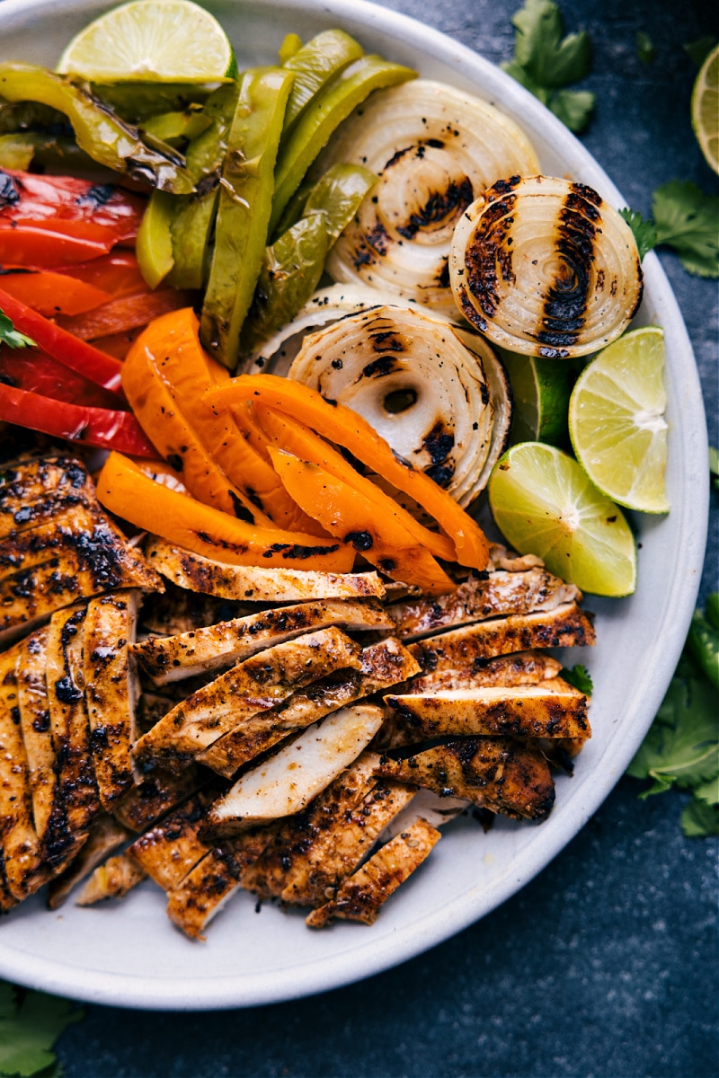 This Chicken Fajita Marinade is unbeatable -- perfect for chicken breasts or thighs AND it's easy to make! Plus, we're sharing how to prepare fajita toppings so you can have the best chicken fajitas right off the grill with no mess in your kitchen! Recipe via ChelseasMessyApron.com #chicken #fajitas #Mexican #dinner #quickandeasy #marinade CLose-up shot of the grilled fajita dinner