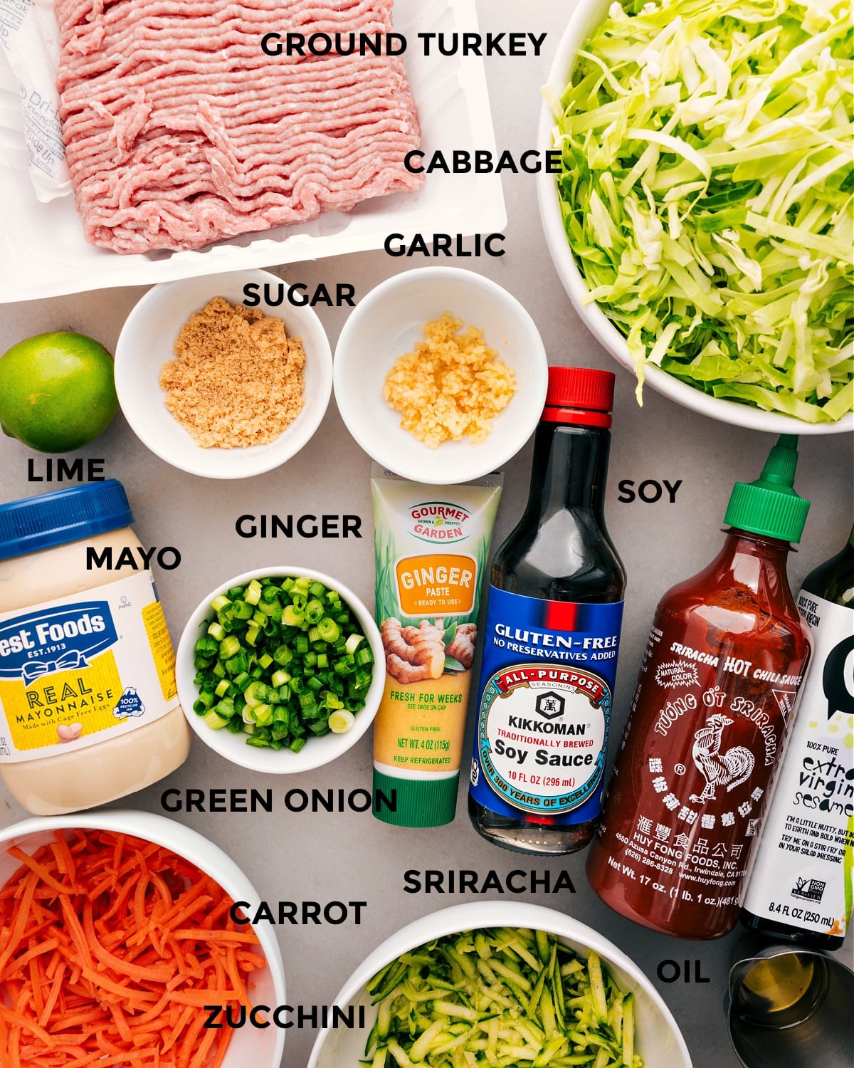 All the ingredients for this recipe are prepped and ready for easy assembly: meat, cabbage, garlic, sugar, mayo, ginger, soy sauce, sriracha, carrots, zucchini, and oil.