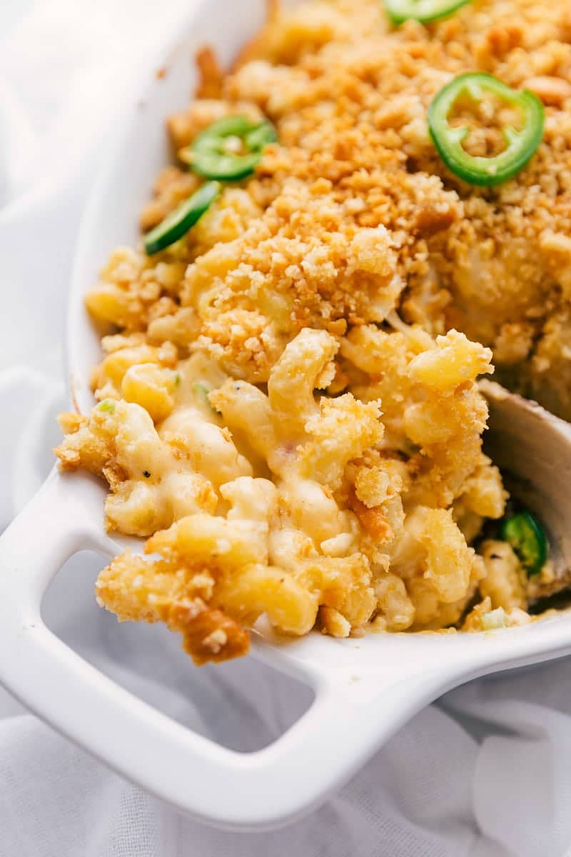 This Jalapeño Popper Mac & Cheese is one for the books! Ultra cheesy, slightly spicy, jalapeño and bacon covered pasta with a crispy buttery topping gets baked to pure cheesy perfection! Recipe via ChelseasMessyApron #dinner #quick #easy #simple #best #panko #familyfriendly #kidfriendly #comfortfood #jalapeno #popper #Macandcheese Jalapeño Popper Mac & Cheese in the dish being scooped up.