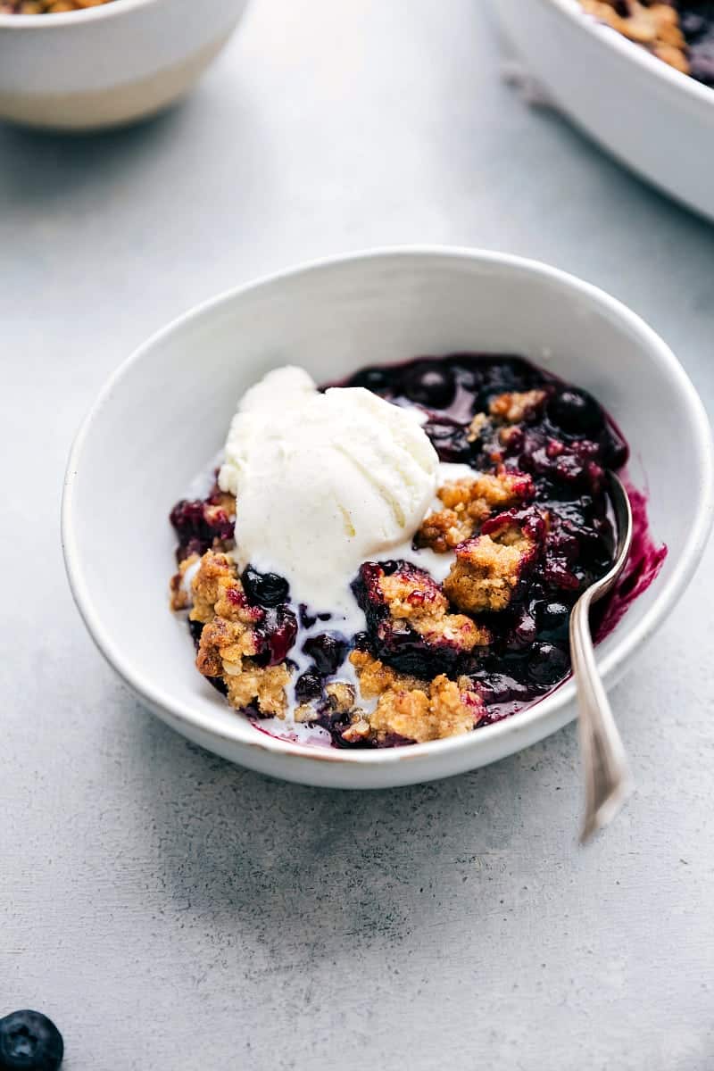 Blueberry Crisp with Ice Cream The finished, freshly baked dessert in a bowl, featuring a golden crumble topping and juicy filling, topped with a scoop of creamy vanilla ice cream, ready to be enjoyed.