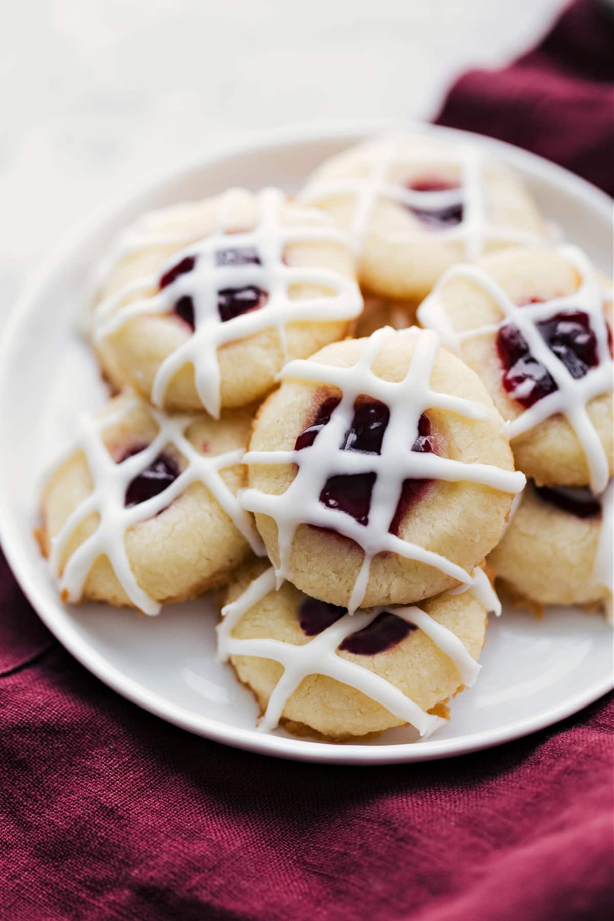 Thumbprint Cookie Recipe with a yummy glaze and raspberry filling sit on a plate.