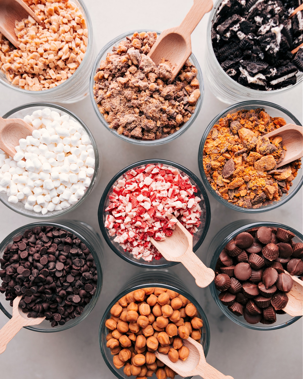 Decadent Choices: Hot Chocolate Bar Toppings Displayed Elegantly Array of toppings in small glass bowls for a hot chocolate bar, including marshmallows, chocolate chips, and sprinkles.