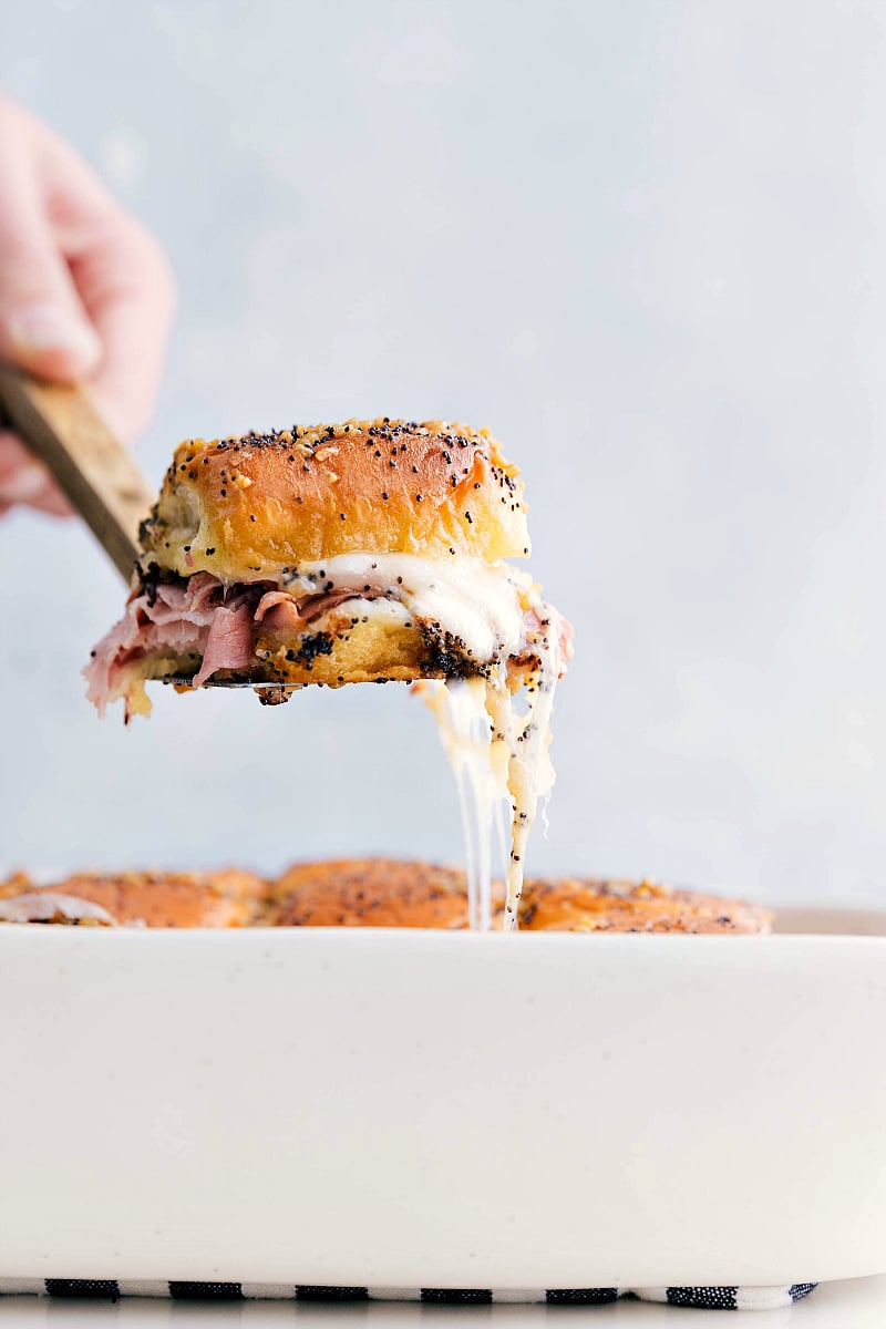 The Best Ham And Cheese Sliders Ham and cheese sliders being picked up with a cheesy pull.