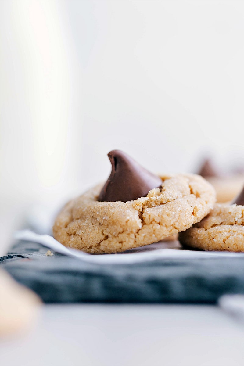 Peanut Butter Blossoms feature a chewy peanut butter base stuffed with a chocolate kiss. The secret to the best blossoms? Keeping the cookies small and rolling them in sugar before baking! Peanut Butter Blossom Cookies