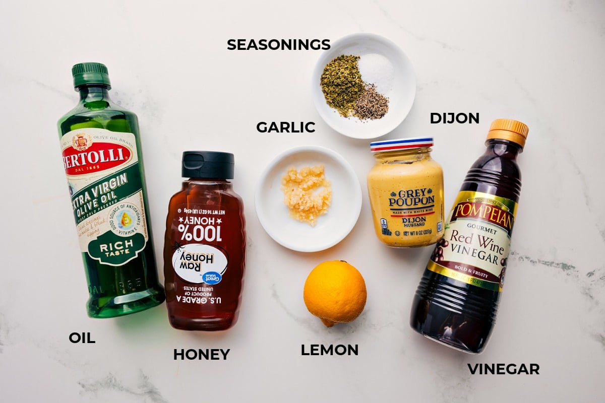 Ingredients In Greek Quinoa Salad Dressing Greek quinoa salad ingredients prepped out for easy assembly including the oil, honey, seasonings, garlic, dijon, vinegar, and lemon.